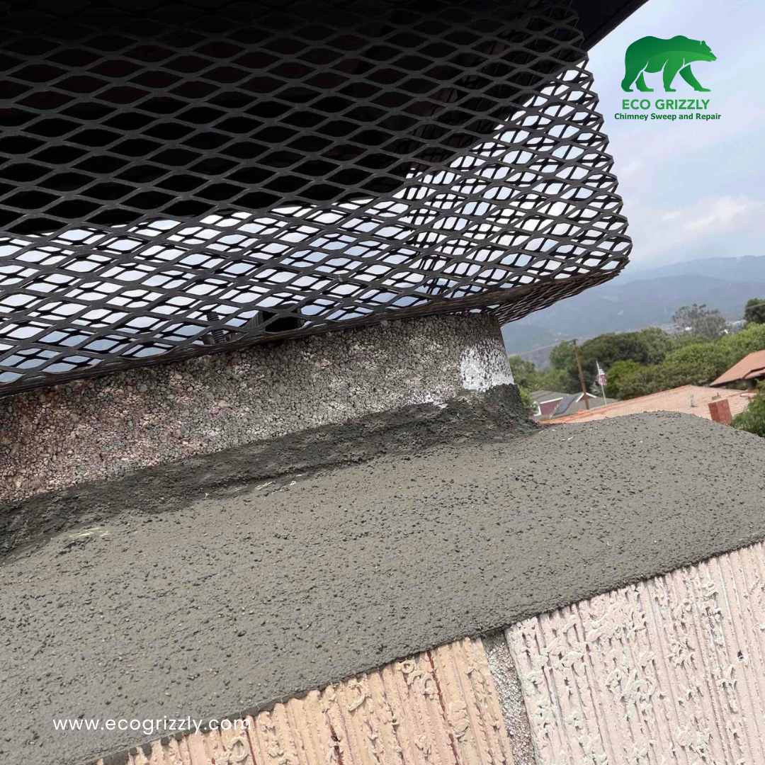 Close-up of chimney crown being repaired with new mortar and a metal mesh cap