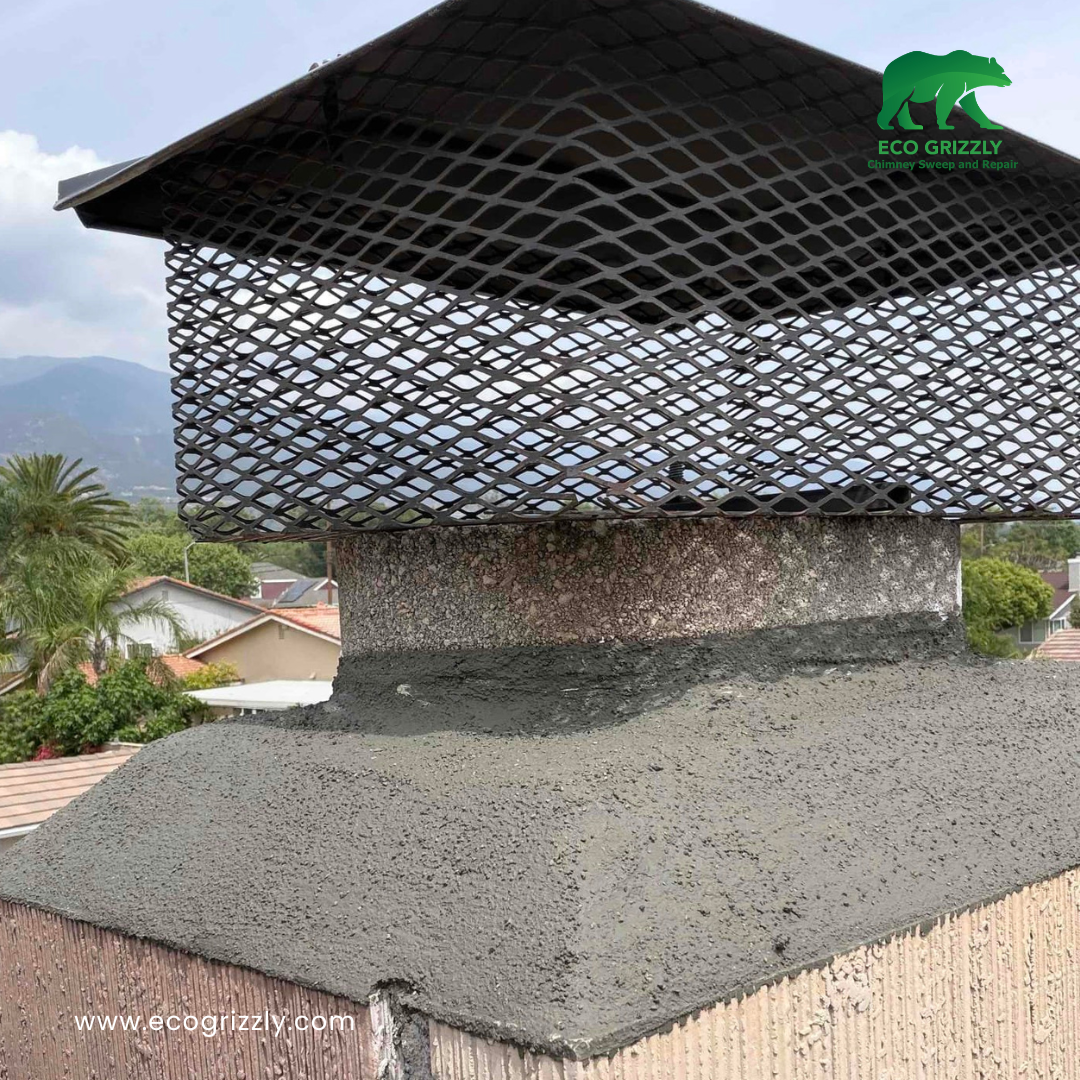 Chimney with newly repaired crown and black mesh cap with houses and mountains behind