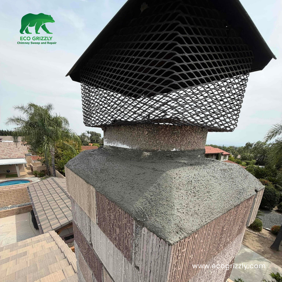 Stone facade chimney with freshly repaired concrete crown and black metal mesh cap