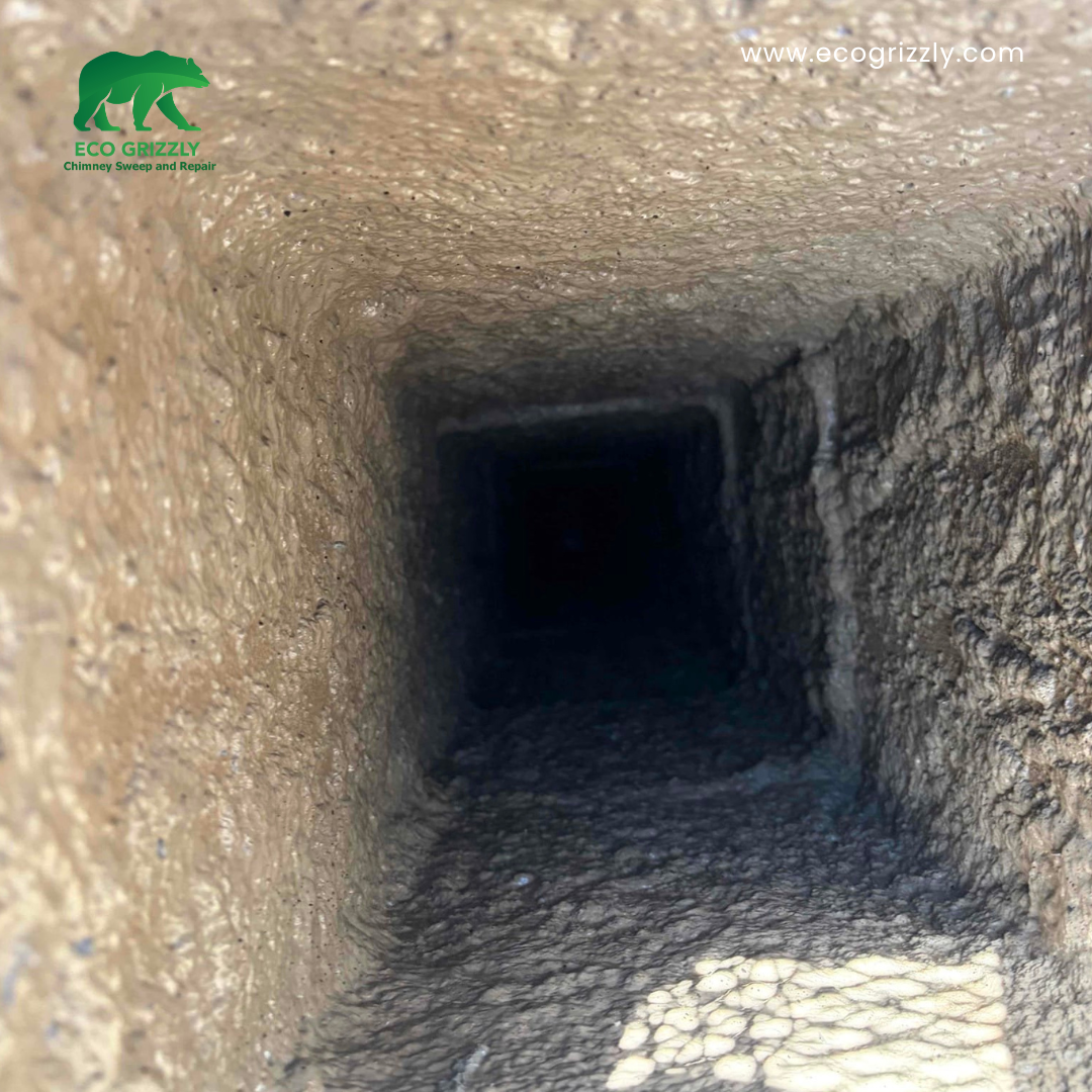 View down into a chimney flue showing accumulated soot and debris during inspection