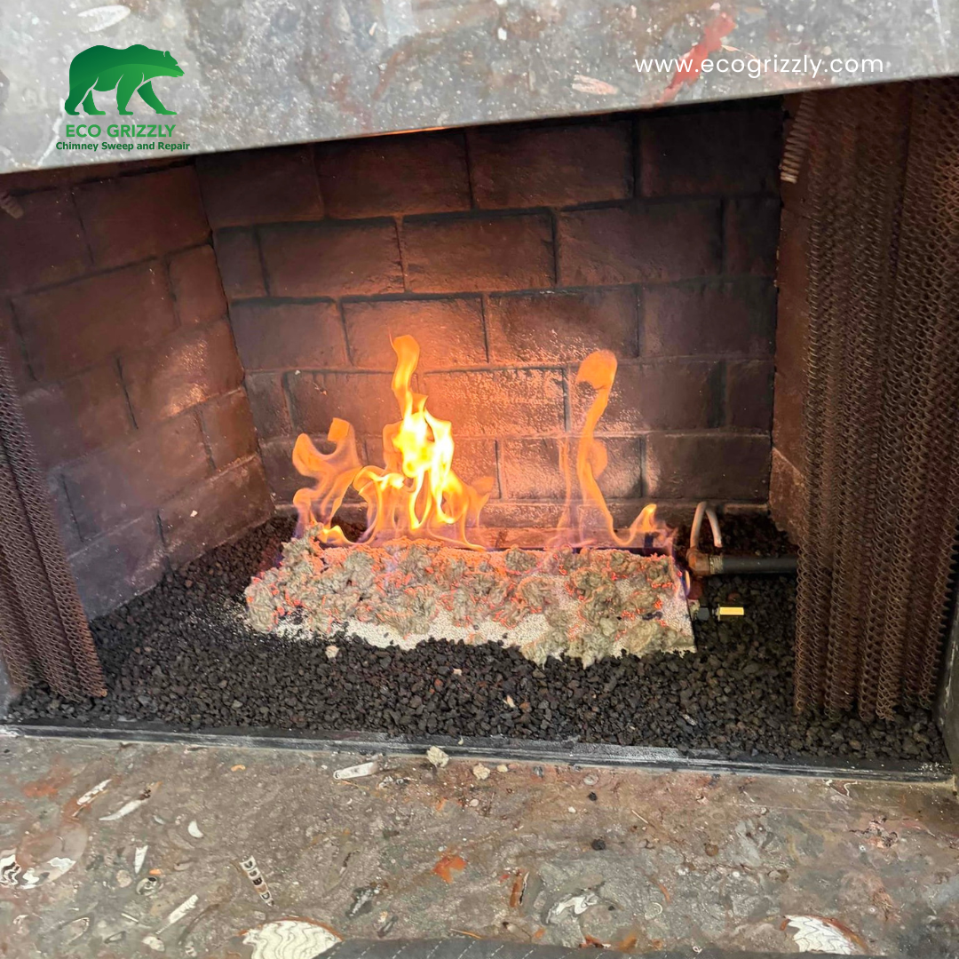 Gas fireplace with realistic logs burning in a dark brick firebox with metal mesh screens