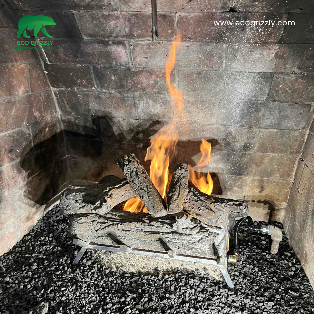Gas fireplace with artificial logs burning in a brick firebox over a bed of dark gravel