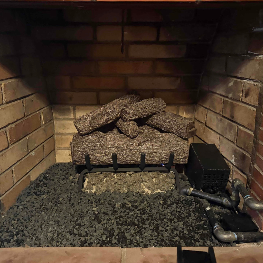 Gas log set with ember bed burning in a residential brick fireplace