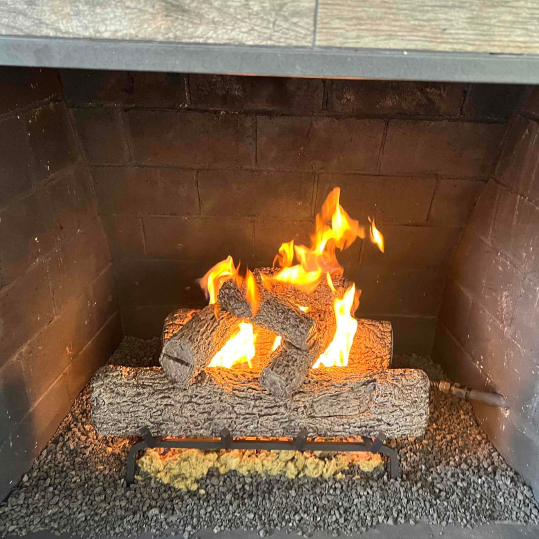 High-output gas log set installed in a large brick fireplace firebox